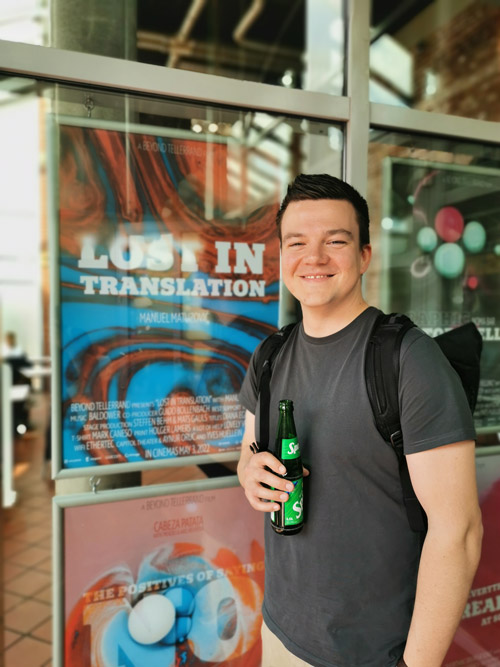 Me standing and smilie in front of a poster made for my talk